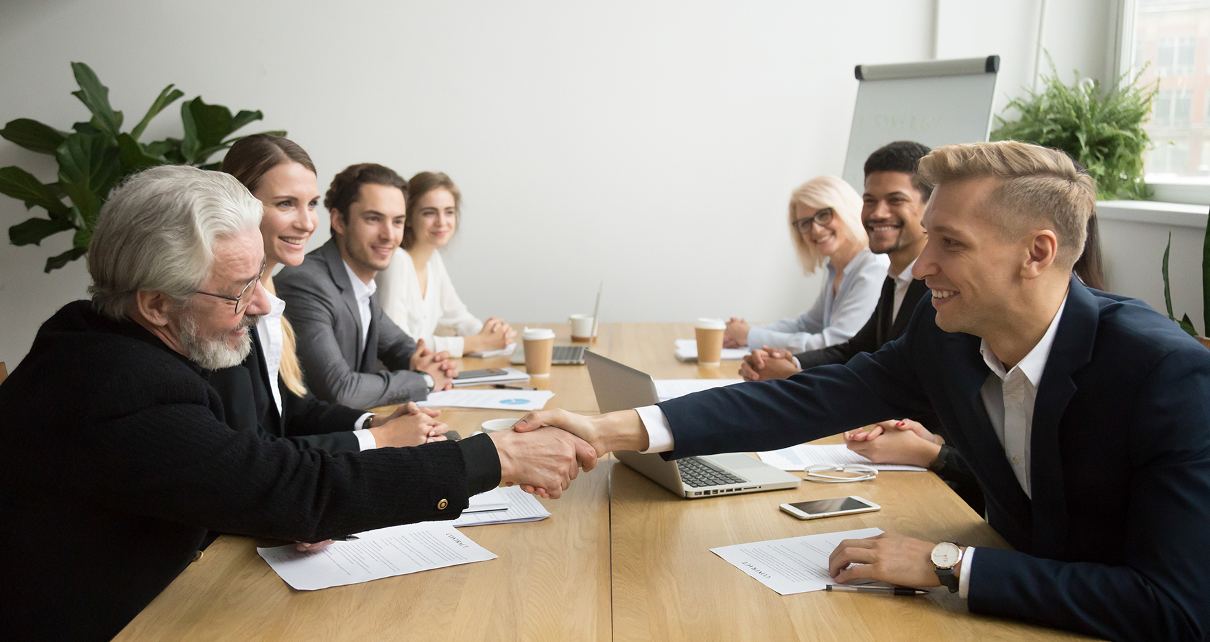 Senior investor buying startup handshaking young entrepreneur at